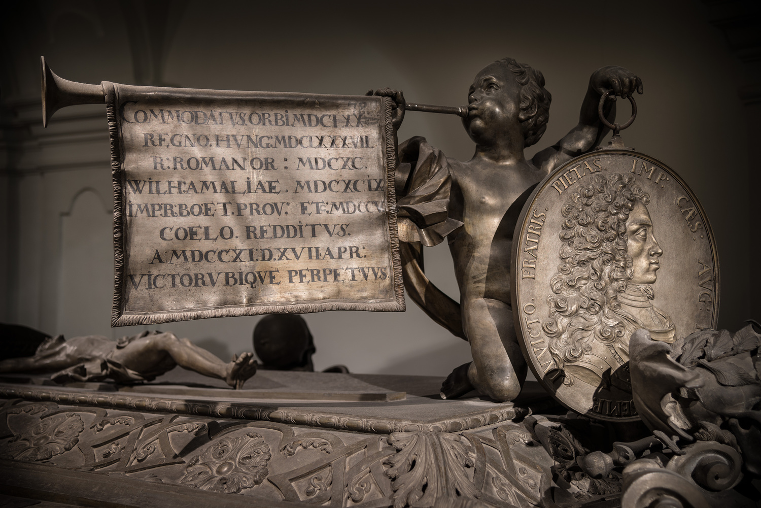 Sargdetails Joseph I., Kaiser, Engel mit Trompete und Porträtmedallion von Joseph I, Kapuzinergruft, Wien, Austria